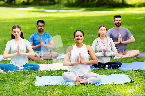 Image of group of happy people doing yoga at summer park