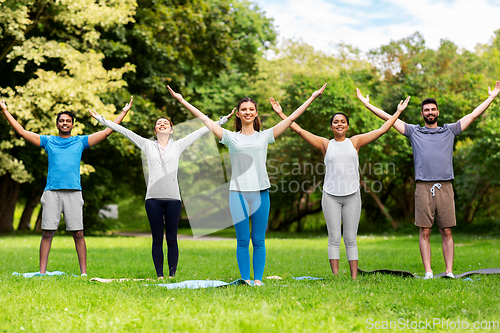 Image of group of people doing yoga at summer park