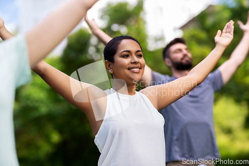 Image of group of people doing yoga at summer park