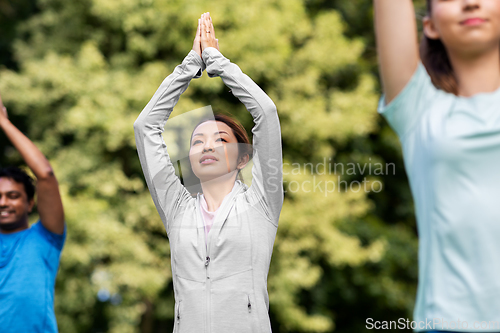 Image of group of people doing yoga at summer park
