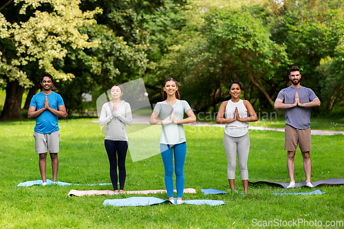 Image of group of people doing yoga at summer park