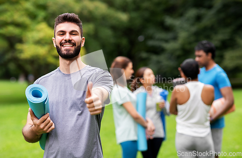 Image of smiling man with yoga mat showing thumbs up