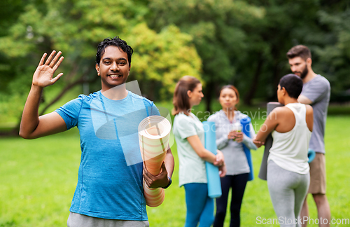 Image of smiling man with yoga mat over group of people