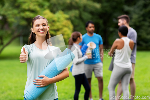 Image of smiling woman with yoga mat showing thumbs up