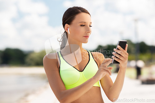 Image of woman with earphones and smartphone doing sports