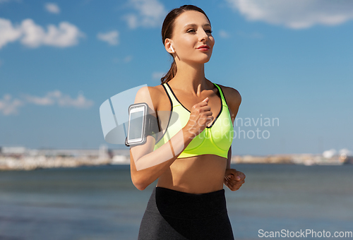 Image of woman with earphones and smartphone running