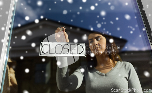 Image of woman hanging banner with closed word on door