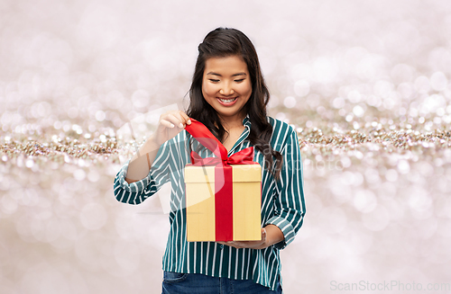 Image of happy asian woman opening gift box