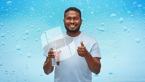 Image of happy african man with water in glass bottle