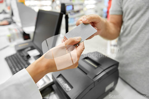 Image of close up of hand giving bank card to pharmacist