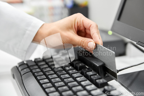 Image of close up of pharmacist's hand swiping credit card