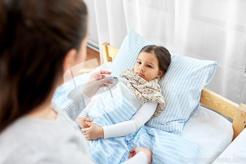 Image of mother measuring temperature of sick daughter