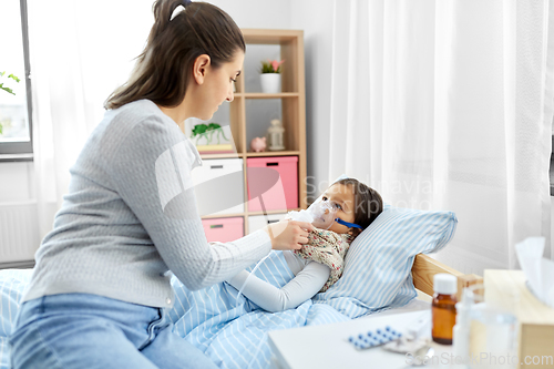 Image of mother and sick daughter with oxygen mask in bed