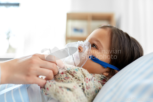 Image of mother and sick daughter with oxygen mask in bed