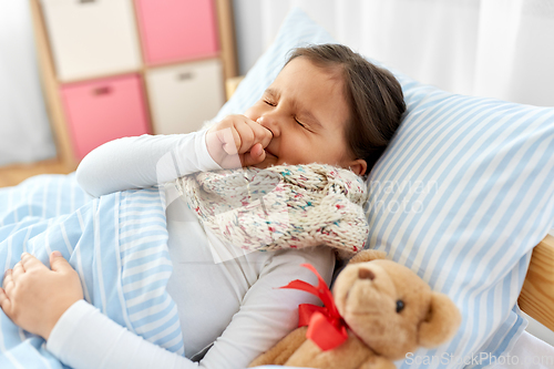 Image of sick coughing girl lying in bed at home