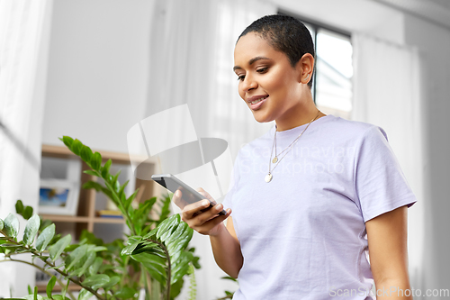 Image of african american woman with smartphone at home