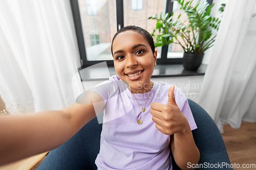 Image of happy african american woman taking selfie at home