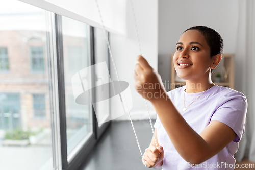 Image of woman opening window roller blinds