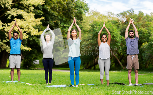 Image of group of people doing yoga at summer park