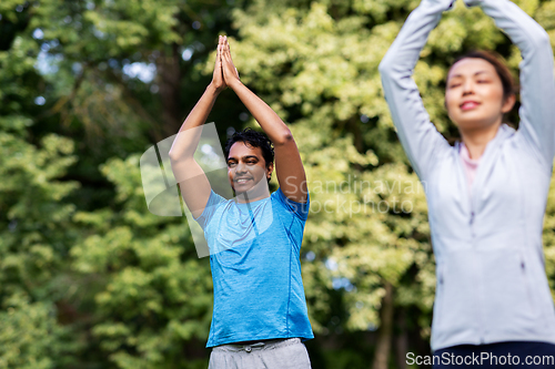 Image of group of people doing yoga at summer park