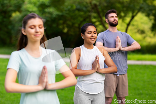 Image of group of people doing yoga at summer park
