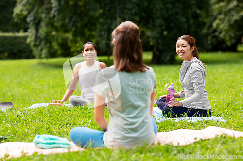 Image of group of people sitting on yoga mats at park