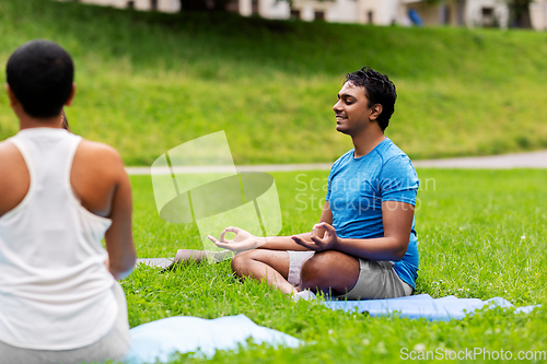 Image of group of people doing yoga at summer park