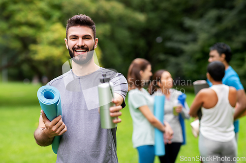 Image of smiling man with yoga mat over group of people