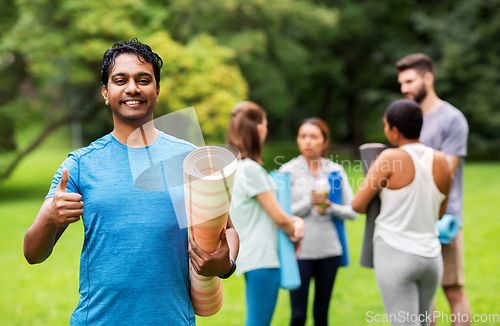 Image of smiling indian man with yoga mat showing thumbs up