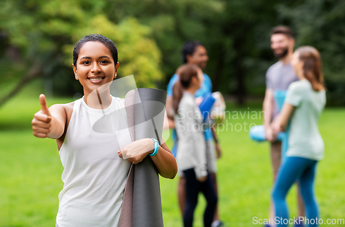 Image of smiling woman with yoga mat showing thumbs up