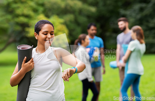 Image of smiling woman with yoga mat and fitness tracker