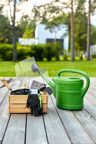 Image of box with garden tools and watering can in summer