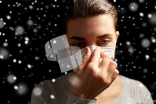 Image of sick woman adjusting protective medical face mask