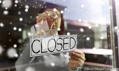 Image of woman hanging banner with closed word on door