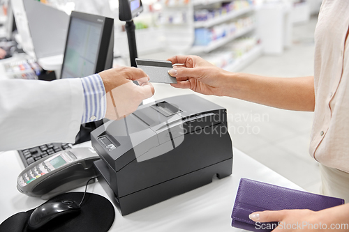 Image of close up of hand giving bank card to pharmacist