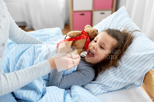 Image of mother giving cough syrup to sick daughter