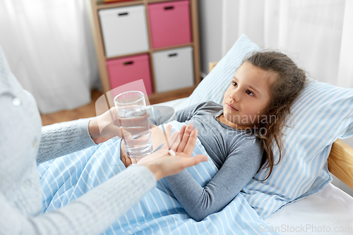 Image of mother giving medicine to sick little daughter