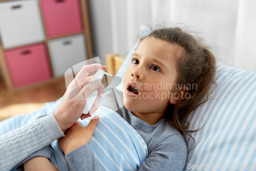 Image of mother with oral spray treats sick little daughter