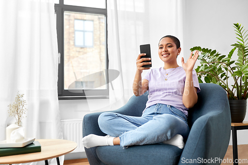 Image of woman with smartphone having video call at home