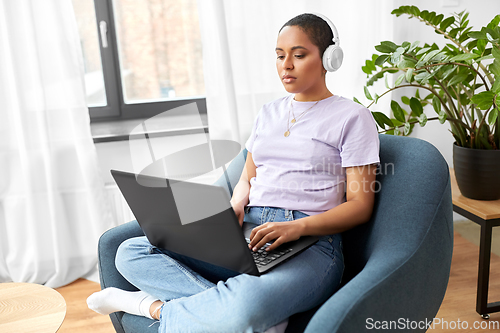 Image of woman with laptop listening to music at home