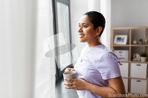 Image of happy woman with coffee looking out of window