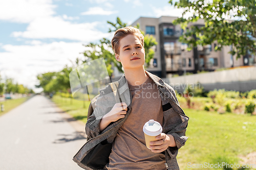 Image of young man with backpack drinking coffee in city