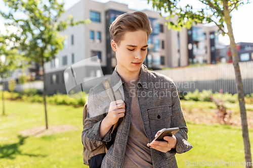 Image of teenage student boy with phone and bag in city