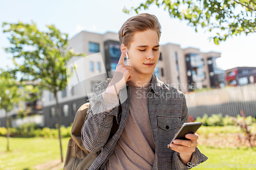 Image of teenage boy with earphones and smartphone in city