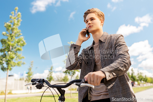 Image of young man with bicycle calling on phone in city