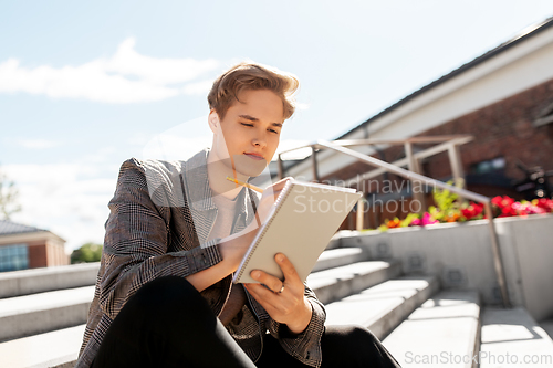 Image of young man with notebook or sketchbook in city