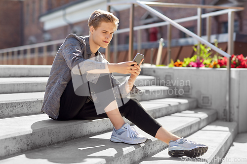 Image of teenage boy using smartphone in city