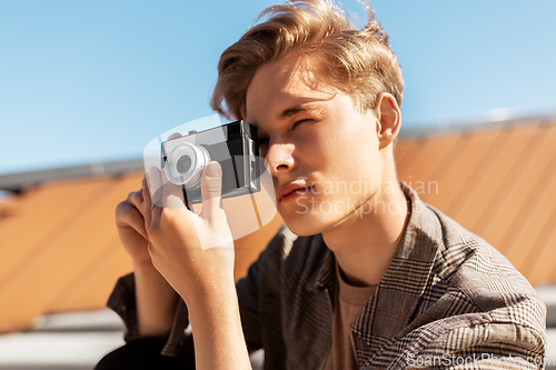 Image of young man with camera photographing in city