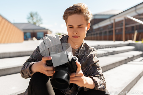 Image of young man with camera photographing in city