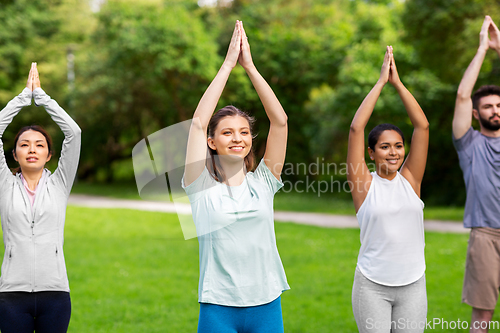 Image of group of people doing yoga at summer park